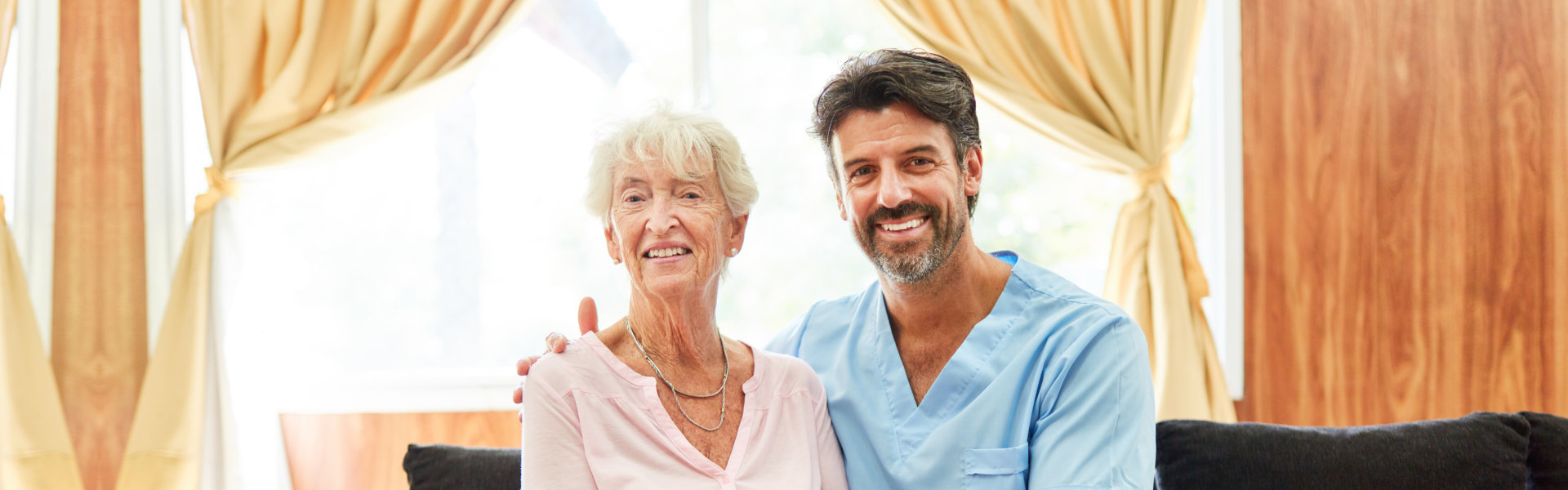 nurse and elderly sitting and looking at the camera