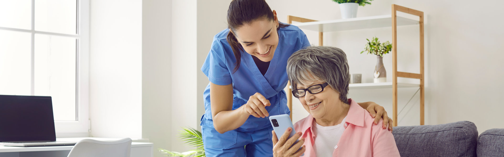 nurse assisting elderly woman holding cellphone